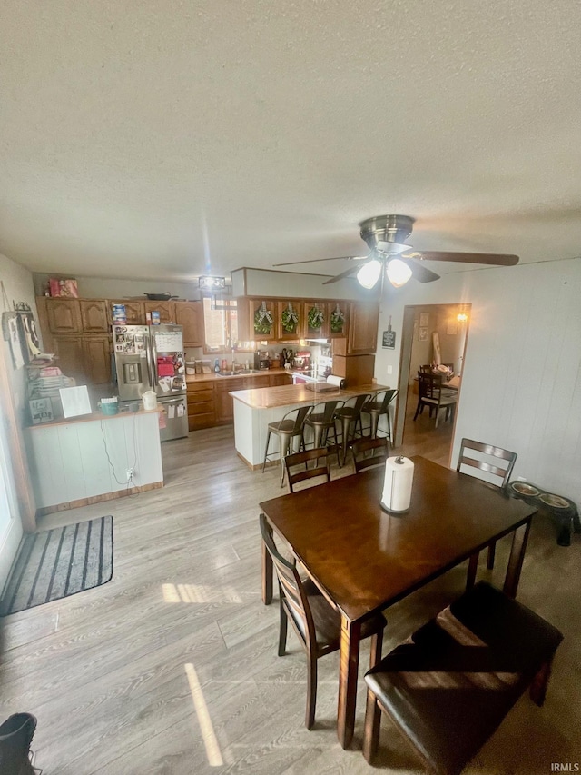 dining area featuring ceiling fan, a textured ceiling, light hardwood / wood-style flooring, and sink