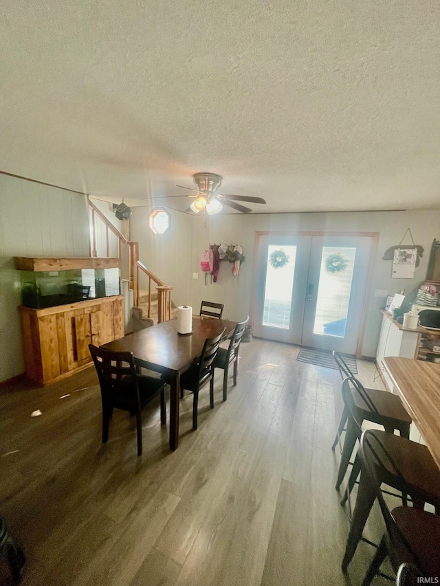 dining space with ceiling fan, a textured ceiling, and light hardwood / wood-style floors