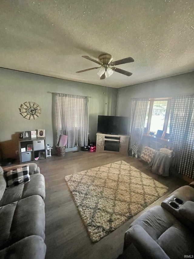 living room featuring ceiling fan, hardwood / wood-style flooring, and a textured ceiling