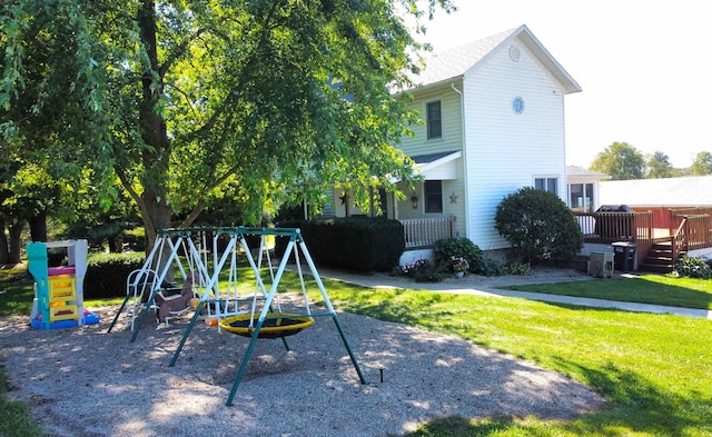 view of playground with a wooden deck and a lawn