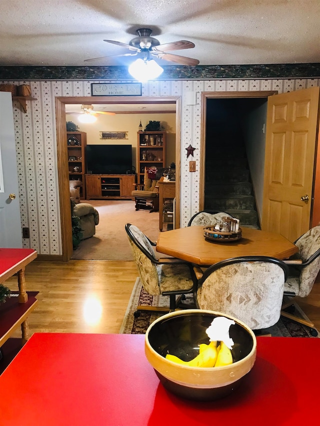 dining space featuring ceiling fan, hardwood / wood-style flooring, and a textured ceiling