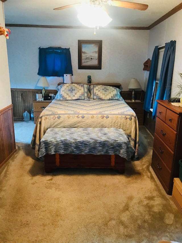 carpeted bedroom featuring ceiling fan, wooden walls, and crown molding