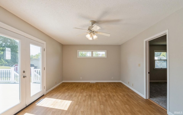 empty room with ceiling fan, a textured ceiling, french doors, and light hardwood / wood-style floors