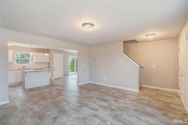 unfurnished living room with sink and light hardwood / wood-style floors