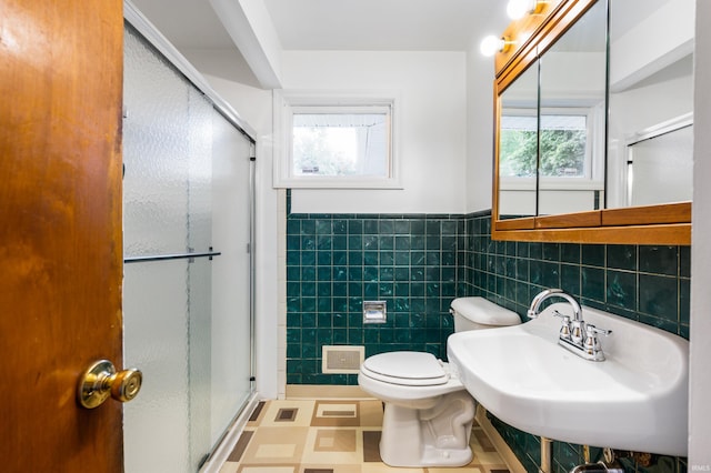 bathroom featuring tile walls, plenty of natural light, a shower with shower door, and toilet