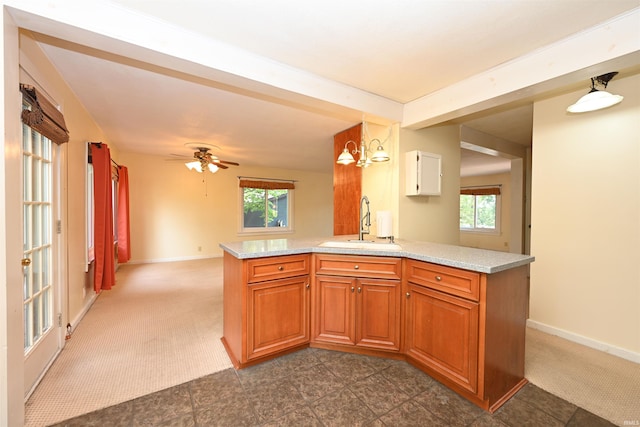 kitchen with kitchen peninsula, dark carpet, sink, and ceiling fan