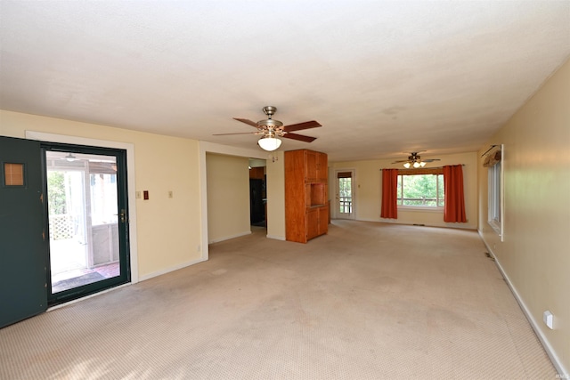 unfurnished living room featuring light carpet, ceiling fan, and plenty of natural light