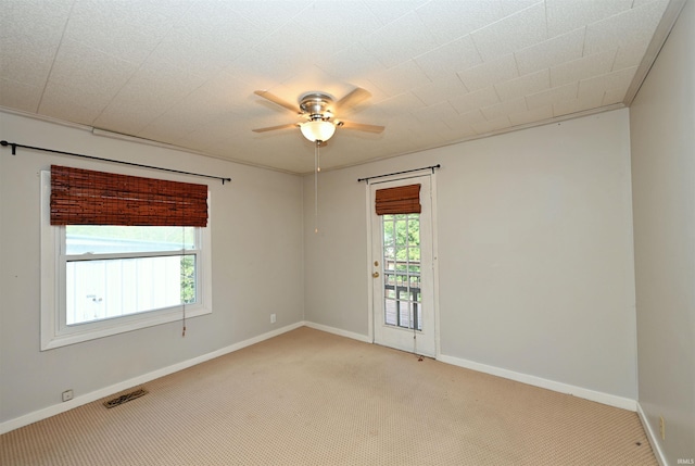 carpeted spare room with ceiling fan and plenty of natural light