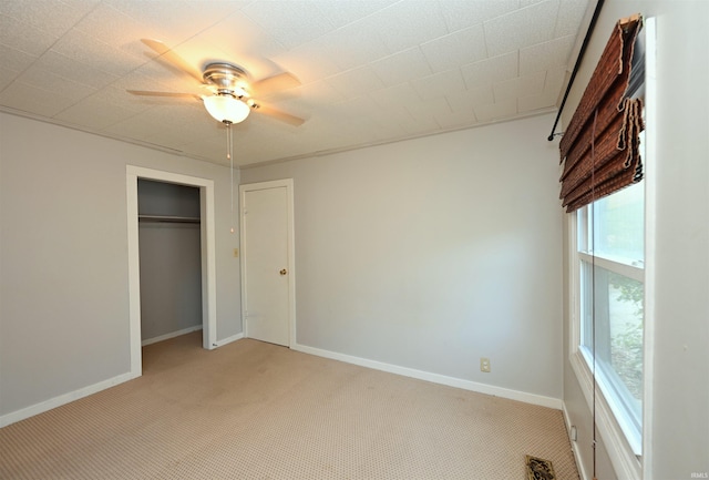 unfurnished bedroom with light carpet, a closet, and ceiling fan