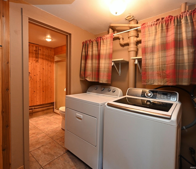 washroom featuring light tile patterned flooring, wood walls, and washing machine and dryer