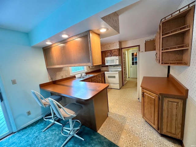 kitchen featuring white appliances, sink, and kitchen peninsula