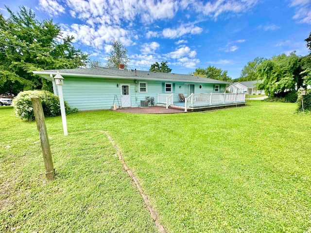 back of property with a deck, a yard, and central AC