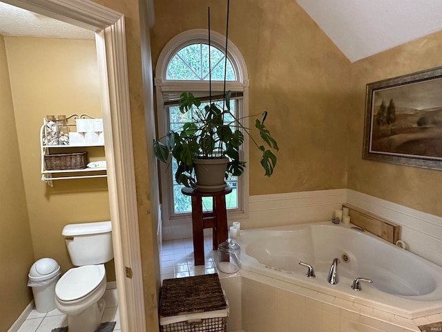 bathroom with vaulted ceiling, toilet, tile patterned floors, and a relaxing tiled tub