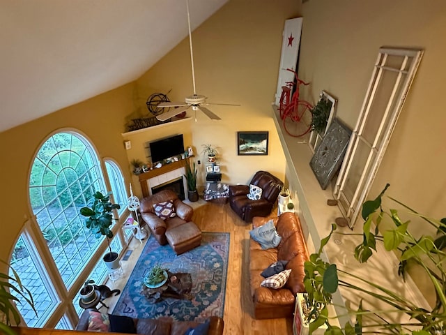 living room with a tile fireplace, ceiling fan, and high vaulted ceiling