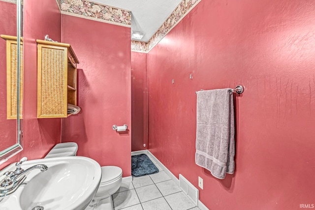 bathroom featuring a textured ceiling, tile patterned flooring, toilet, and sink