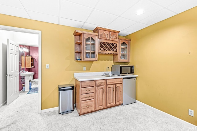 kitchen with appliances with stainless steel finishes, a paneled ceiling, sink, and light colored carpet