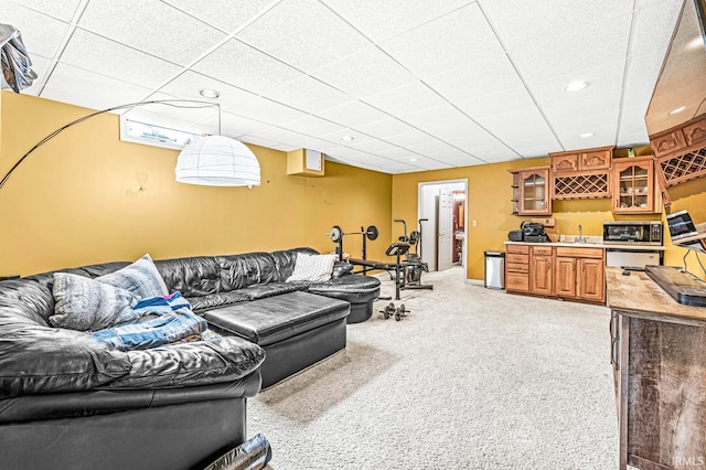 carpeted living room featuring a paneled ceiling and indoor bar