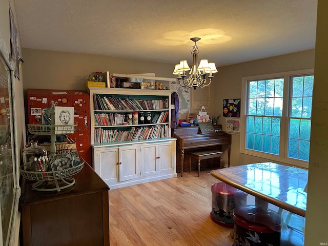 miscellaneous room with an inviting chandelier, light hardwood / wood-style floors, and a textured ceiling