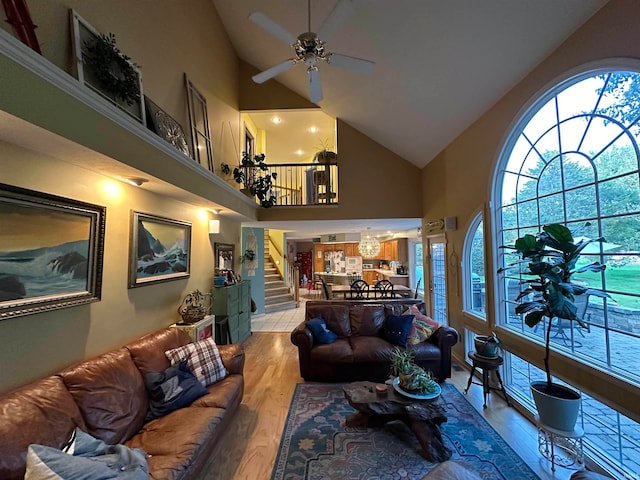 living room with light wood-type flooring, ceiling fan, and high vaulted ceiling