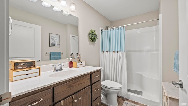 bathroom featuring wood finished floors, a shower stall, toilet, and vanity