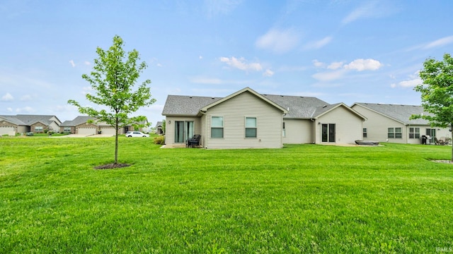 back of property with a shingled roof and a lawn