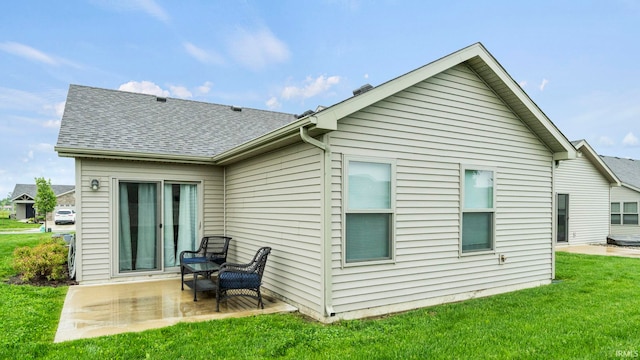back of house featuring a patio, a yard, and a shingled roof