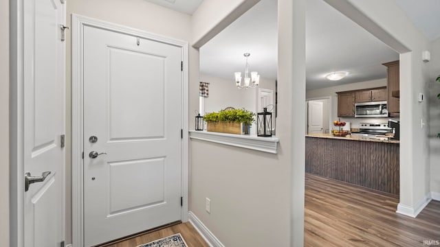 entryway featuring an inviting chandelier, wood finished floors, and baseboards