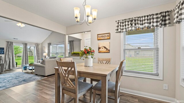dining room with visible vents, baseboards, vaulted ceiling, wood finished floors, and a notable chandelier