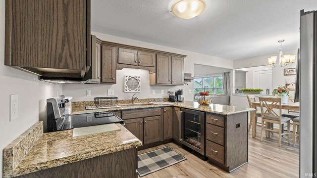 kitchen with wine cooler, kitchen peninsula, light wood-type flooring, dark brown cabinets, and sink