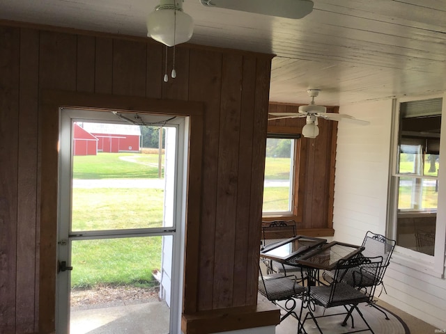 dining space with ceiling fan and wood walls