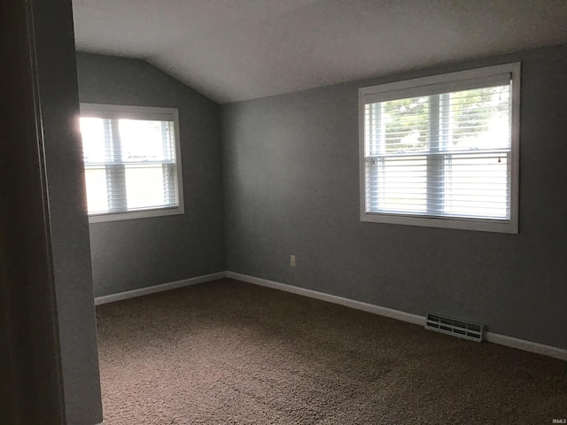 carpeted spare room featuring vaulted ceiling