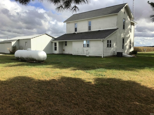 rear view of house with central AC and a yard