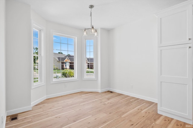 unfurnished dining area with light hardwood / wood-style floors and a chandelier