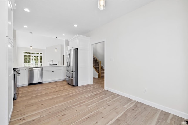 kitchen featuring light hardwood / wood-style floors, white cabinetry, stainless steel appliances, decorative light fixtures, and sink