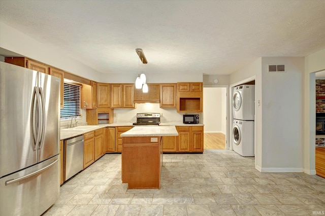 kitchen with stacked washer and clothes dryer, a kitchen island, stainless steel appliances, decorative light fixtures, and sink