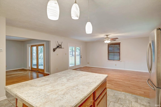 kitchen with stainless steel refrigerator, light hardwood / wood-style flooring, french doors, and decorative light fixtures