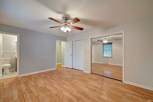 unfurnished bedroom featuring ceiling fan, light hardwood / wood-style flooring, two closets, and ensuite bathroom