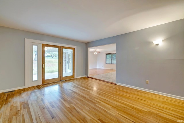 empty room with light hardwood / wood-style flooring, a wealth of natural light, and ceiling fan