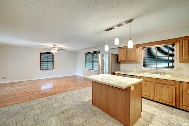 kitchen featuring ceiling fan, a center island, plenty of natural light, and stainless steel fridge