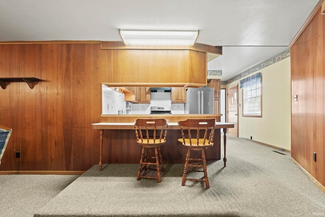 kitchen with stainless steel fridge, kitchen peninsula, and wood walls