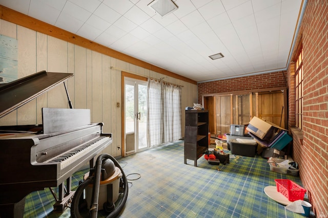 interior space with carpet, wood walls, and brick wall