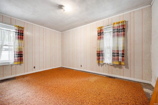 spare room with carpet flooring, wooden walls, and crown molding