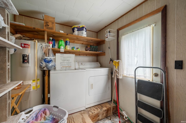 clothes washing area featuring heating unit, water heater, wood walls, and independent washer and dryer