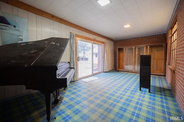 living area with carpet and brick wall