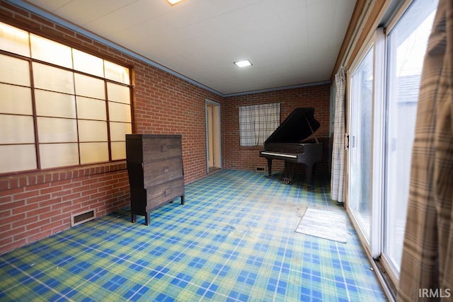 miscellaneous room with carpet, crown molding, and brick wall