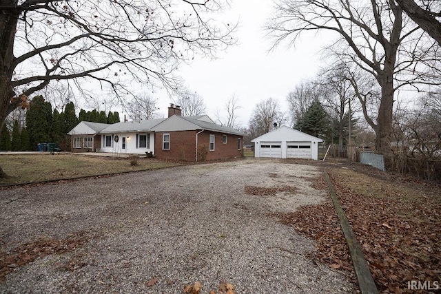 single story home featuring covered porch, a garage, and an outbuilding