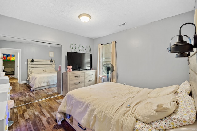 bedroom with dark hardwood / wood-style flooring, a textured ceiling, and a closet