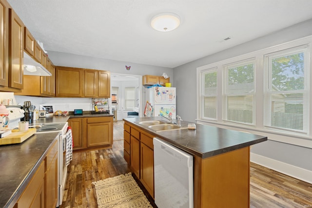 kitchen with white appliances, dark hardwood / wood-style floors, a kitchen island with sink, and sink