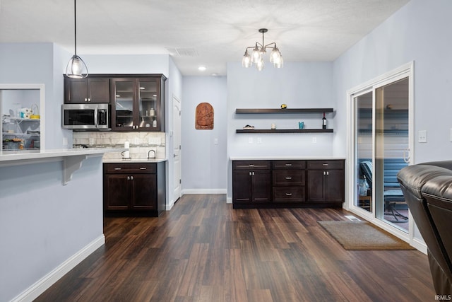 kitchen with dark brown cabinetry, decorative light fixtures, and dark hardwood / wood-style flooring