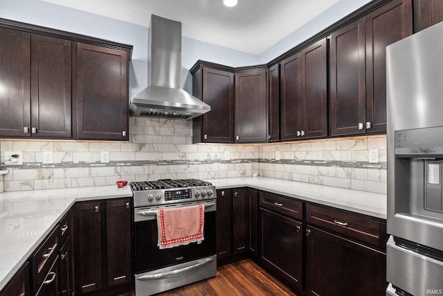 kitchen with dark hardwood / wood-style floors, wall chimney exhaust hood, decorative backsplash, appliances with stainless steel finishes, and light stone countertops